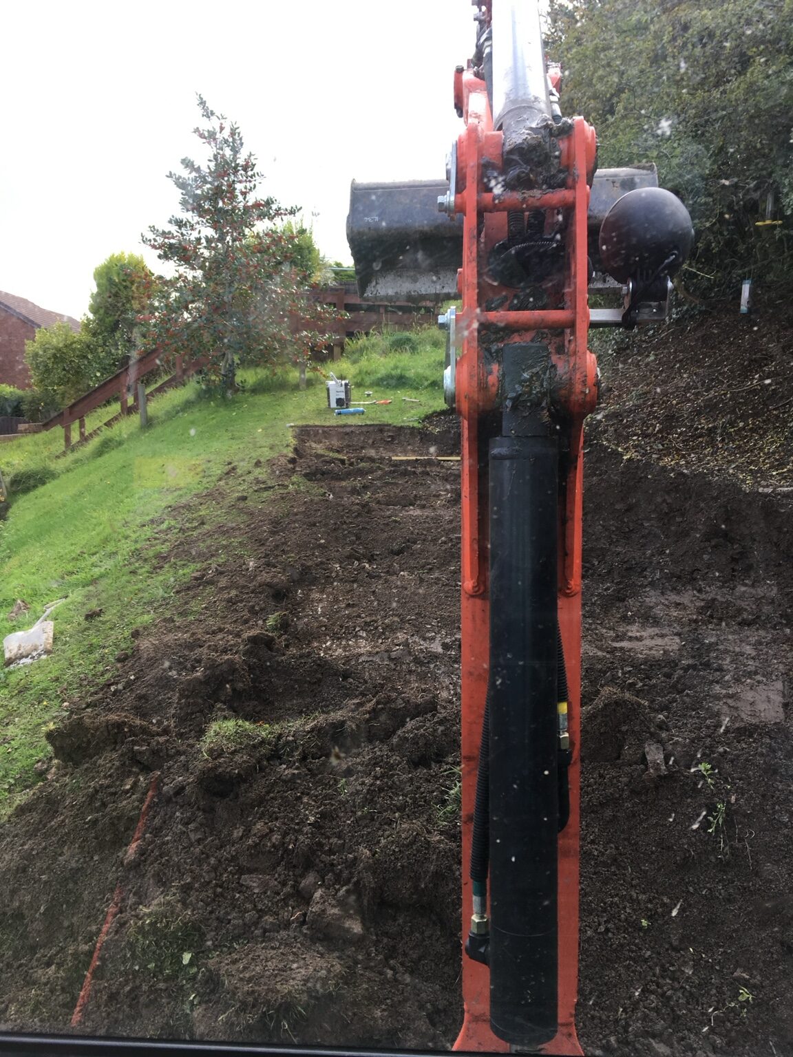 Excavator forming new levels on a sloping garden